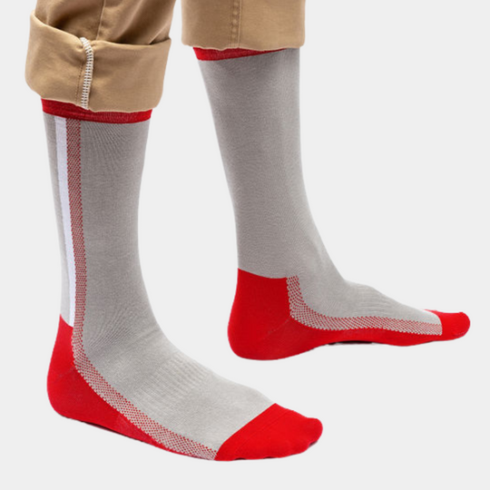 A pair of legs wearing light gray socks with red heels, toes, and accents, shown with beige pants slightly rolled up.