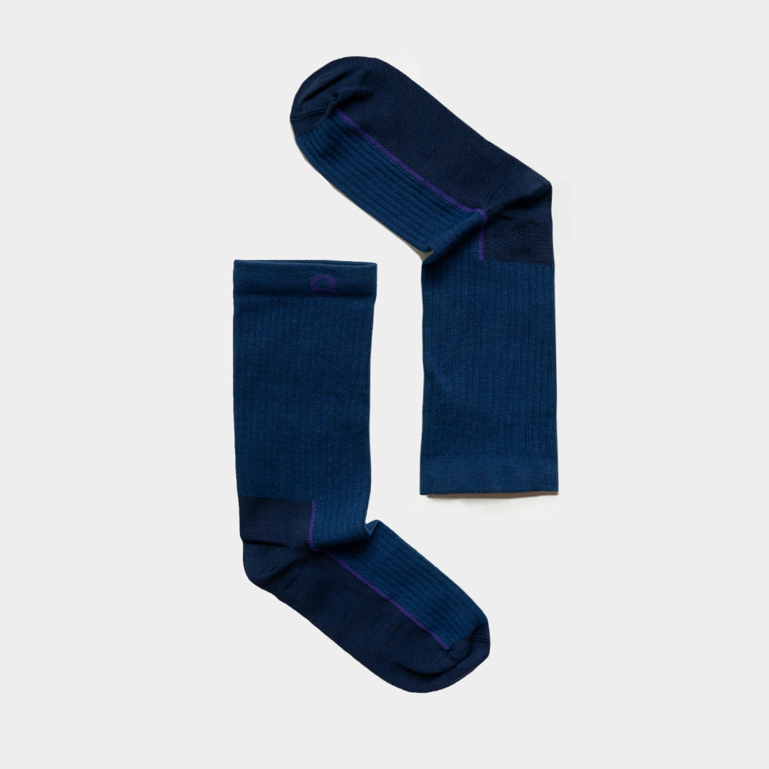 Two dark blue socks with lighter blue heels and toes are arranged on a white background to form the shape of a right angle.