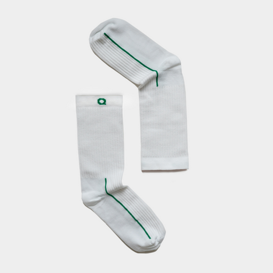 A pair of white crew socks with green lines along the sides and small green squares near the top, laid flat on a plain white background.