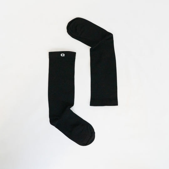 Two black socks arranged on a white background, with one sock positioned vertically and the other horizontally, forming the shape of an uppercase letter L.