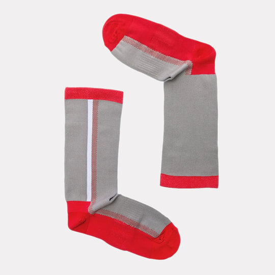 Two gray socks with red toes, heels, and cuffs are arranged on a white background in the shape of an uppercase letter “L.” One sock has a white vertical stripe.