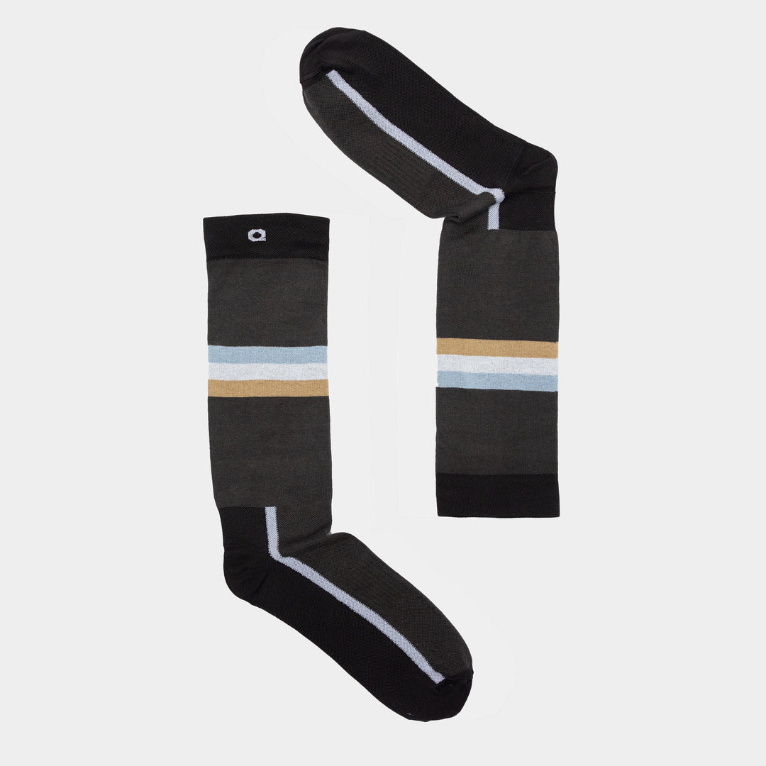 Two dark gray socks with black toes and heels, each featuring a horizontal light blue and tan stripe near the top, are arranged on a white background to form the shape of the number 7.