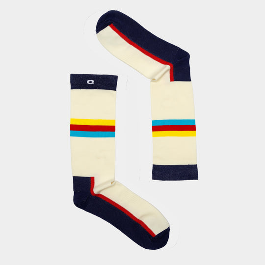 Two cream-colored socks with navy toes, heels, and cuffs, featuring horizontal red, yellow, and blue stripes across the middle, are arranged on a light background to form the number 1.