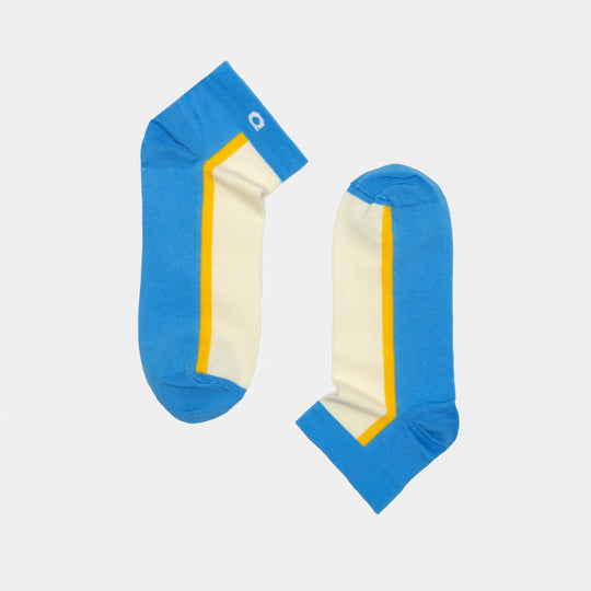 A pair of ankle socks with blue toes, heels, and cuffs, cream-colored bodies, and a yellow stripe running along the sides. The socks are laid flat on a white background, facing opposite directions.