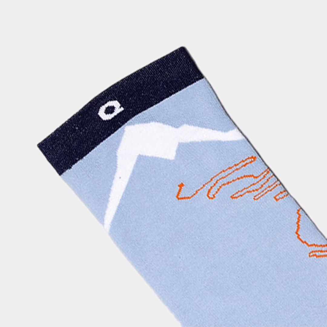 A light blue sock with a dark navy cuff, featuring a white mountain design and orange lines on the side.