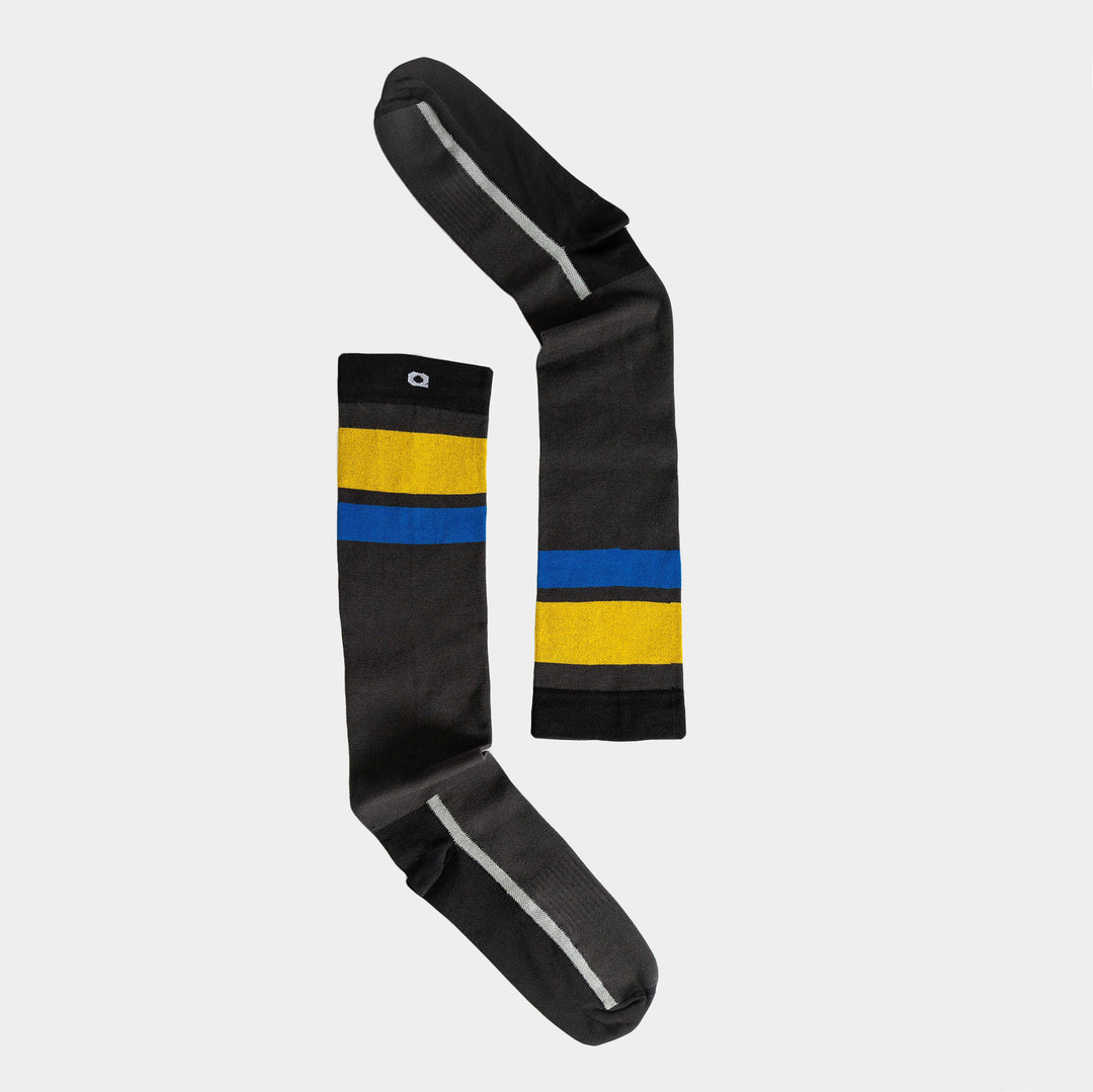 A pair of mismatched knee-high socks, both mainly black with one sock featuring yellow and blue horizontal stripes, laid flat on a plain white background.