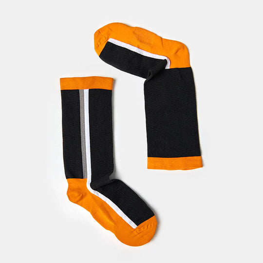 A pair of knee-high socks with black bodies, orange toes, heels, and cuffs, and a single white vertical stripe running down each sock. The socks are laid flat on a light gray background.