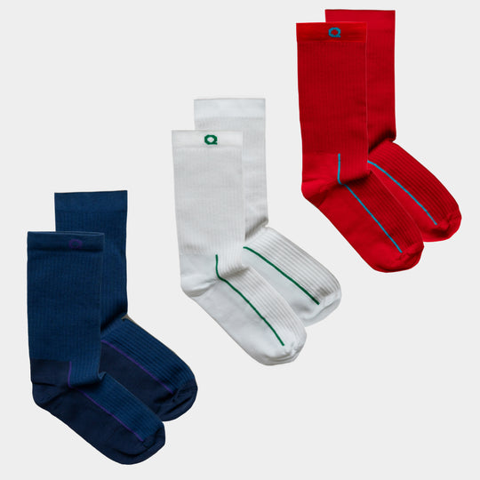 Three pairs of crew socks are displayed: one pair is navy blue with a purple stripe, one pair is white with a green stripe, and one pair is red with a blue stripe. Each pair is neatly folded and placed side by side.