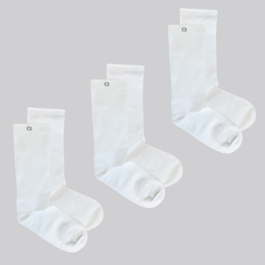 Three pairs of plain white crew socks are displayed on a light gray background, arranged side by side, each pair stacked with one sock slightly overlapping the other.