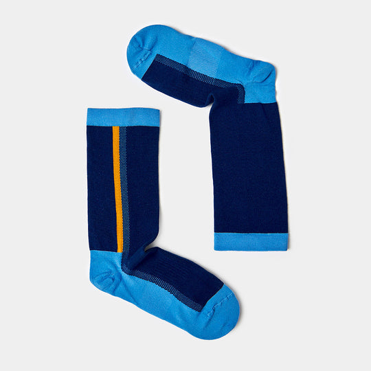 Two blue socks with light blue toes, heels, and cuffs are laid out to form the shape of the letter L. One sock has a yellow and orange vertical stripe. The background is light gray.